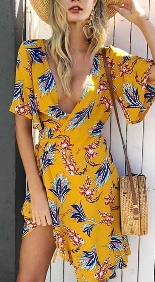 Woman wearing yellow and blue floral deep v-neck short-sleeved mini dress. Pic by lovestoreyofficial