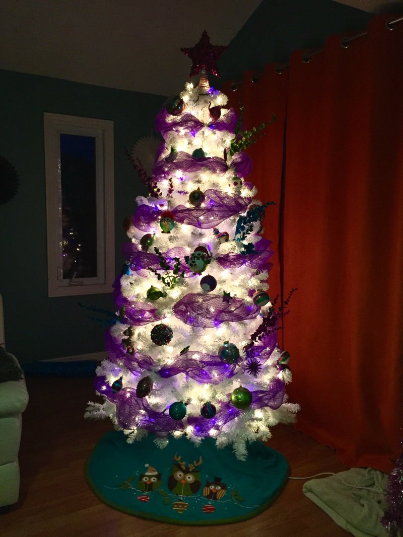 White Christmas tree with white and purple lights and purple ribbon.