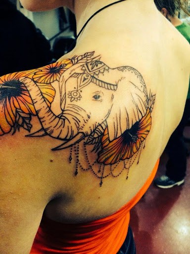 Feminine Elephant tattoo with flowers on upper back and shoulder.