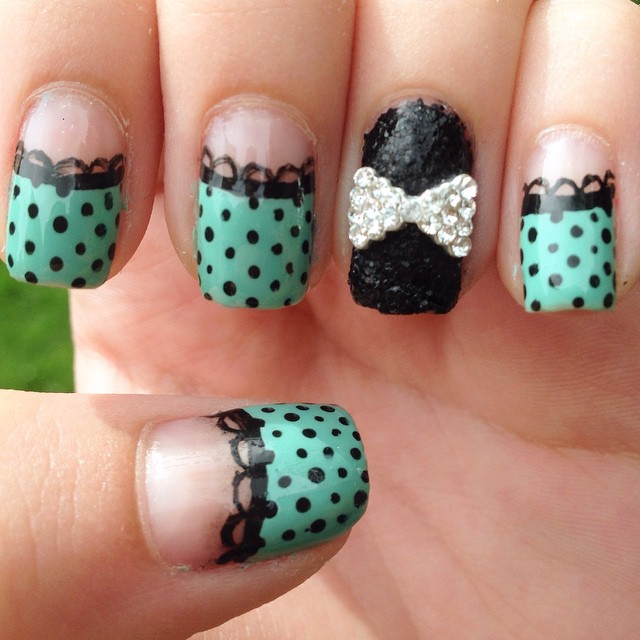 Black polka dot nails over turquoise with a lace-like border and a black sparkly accent nail with a bow. #nails #nailart #sparklynails #sparklynailart