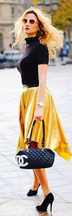 Woman in black and yellow dress holding black bag.