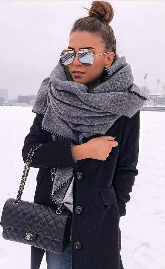 Woman in gray scarf and black button-up overcoat.