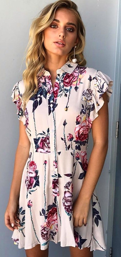 Woman in white and red floral dress standing.