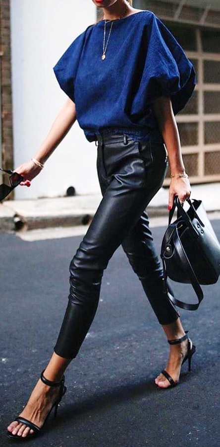 Woman walking wearing blue crew-neck shirt and black faux leather skinny jeans outfit.