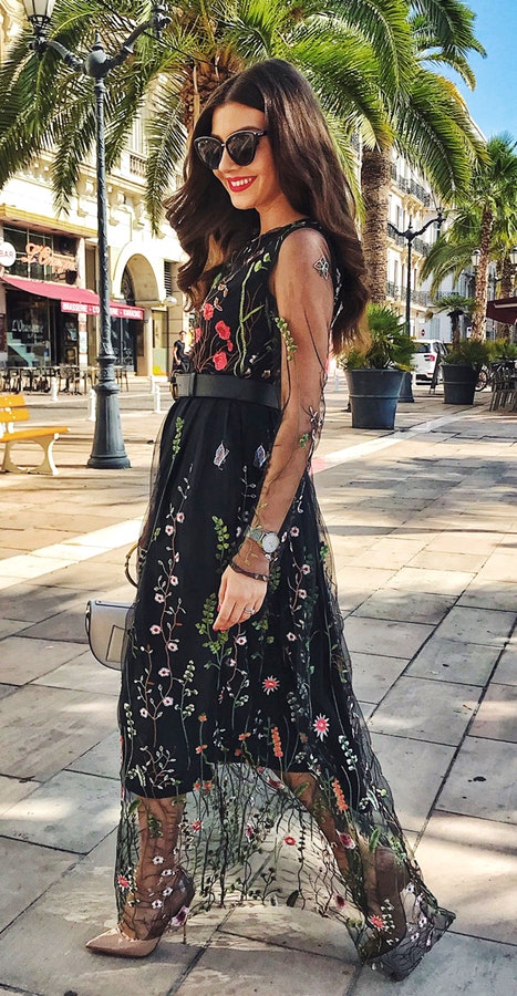 Woman wearing black, gray, and pink floral sleeveless dress walking on street during daytime.