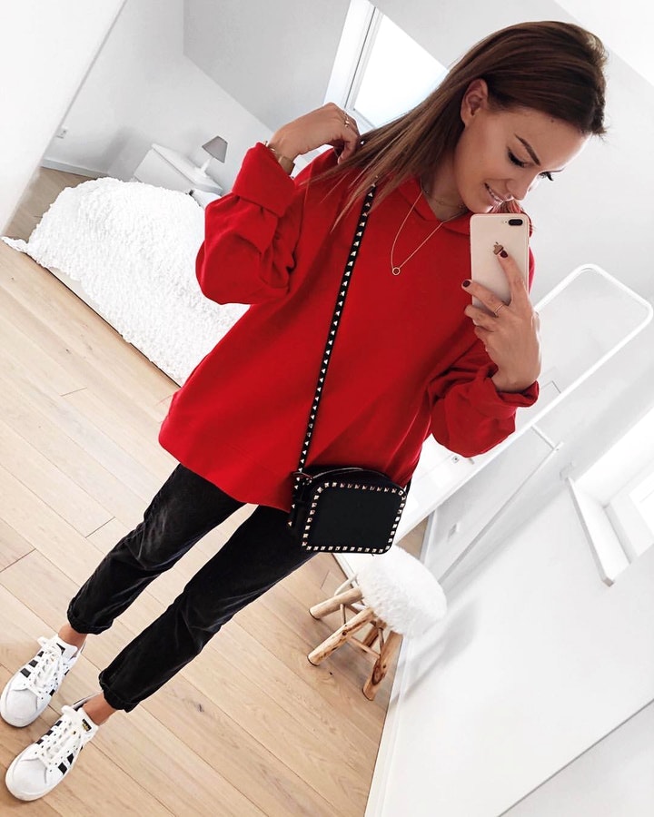 Woman wearing red pullover hoodie and black pants.