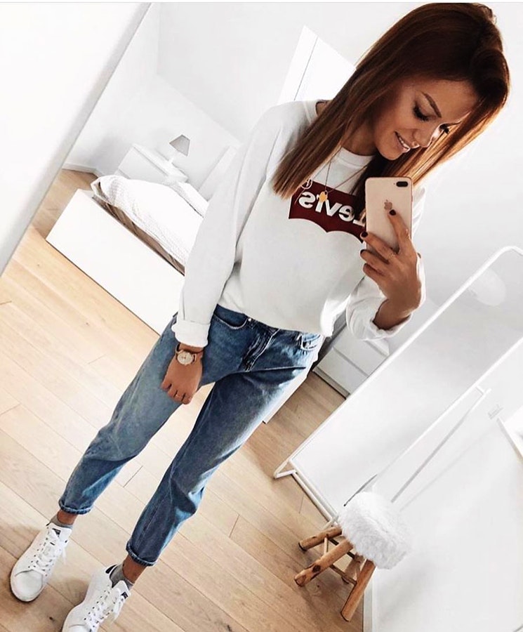 Woman wearing white Levis crop top, washed jeans and pair of white casual sneakers outfit.