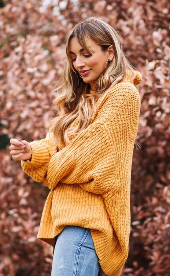 Woman wearing yellow turtle-neck sweater and blue-washed bottoms.