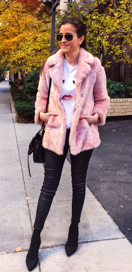 Woman wears pink fur coat and black leather fitted pants.