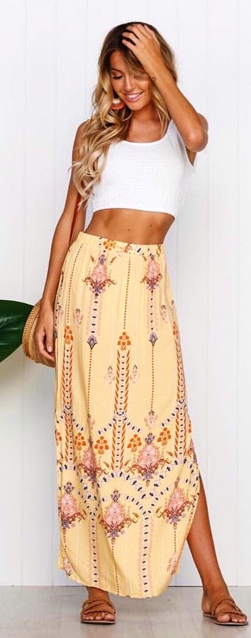 White crew-neck sleeveless crop top and beige floral maxi skirt.