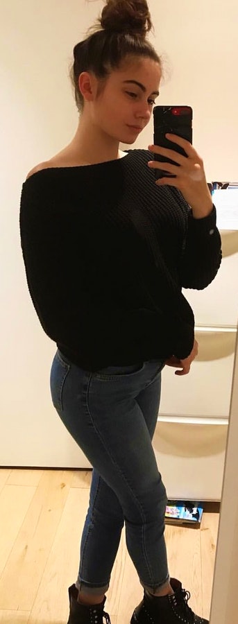 Black scoop-neck sweater with blue denim jeans.