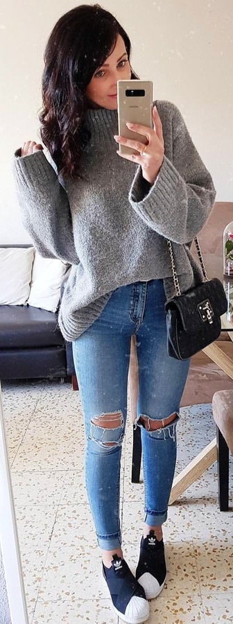 Gray sweater, blue distressed jeans, and pair of black low-top sneakers.