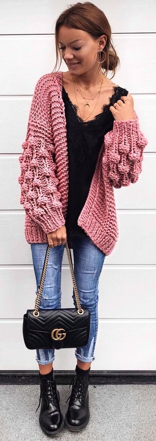 Red knit cardigan, black shirt, blue denim jeans, black leather boots, and black leather handbag outfit.