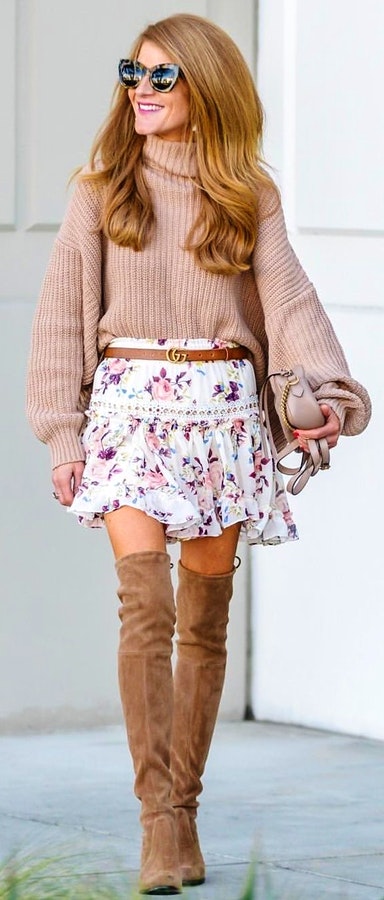 Woman in brown sweater wearing white and pink floral mini skirt.