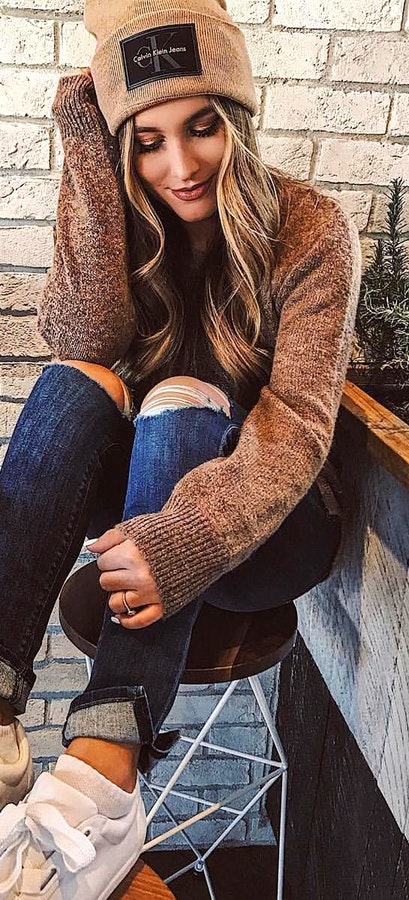 Woman wearing brown sweater and blue denim jeans.