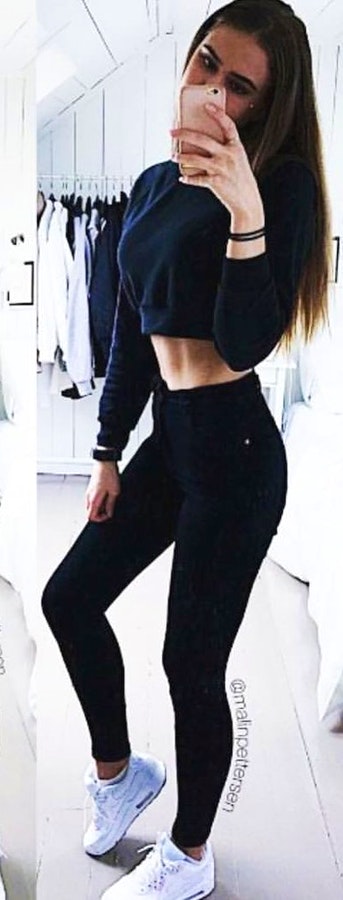 Woman wearing long-sleeved crop top and black leggings with white sneakers outfit.