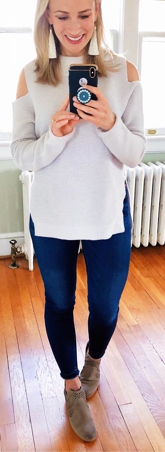 Woman wearing white cold-shoulder shirt and blue jeans.