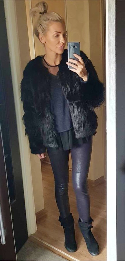 Women's black fur jacket, black pants, and black boots.