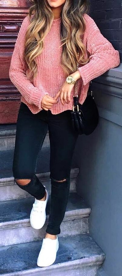 Women's pink crewneck sweater and distressed black jeans.