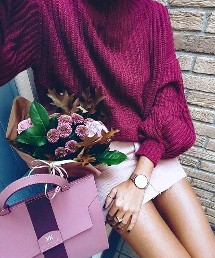 Women's red knit long-sleeve shirt, pink leather tote bag, round analog watch, and pink miniskirt.