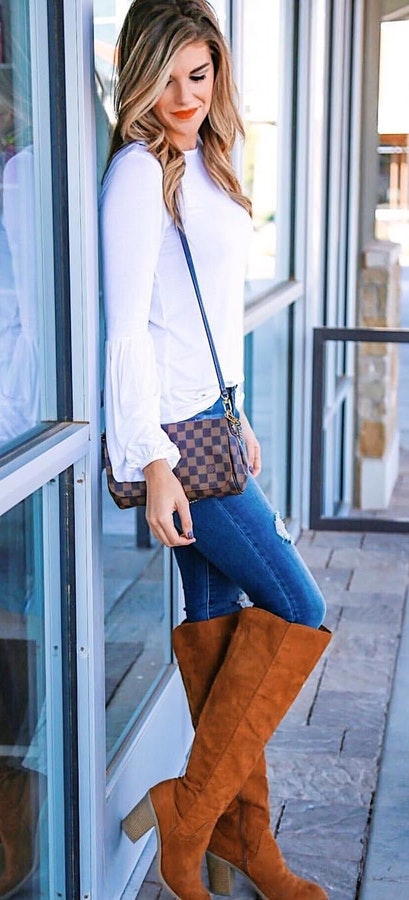 Women's white crew-neck long-sleeved blouse and blue denim jeans.