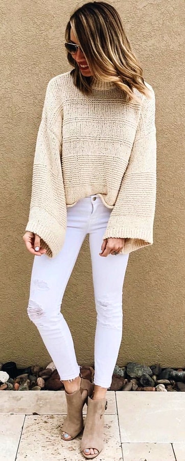 Woman in beige sweater and white jeans.