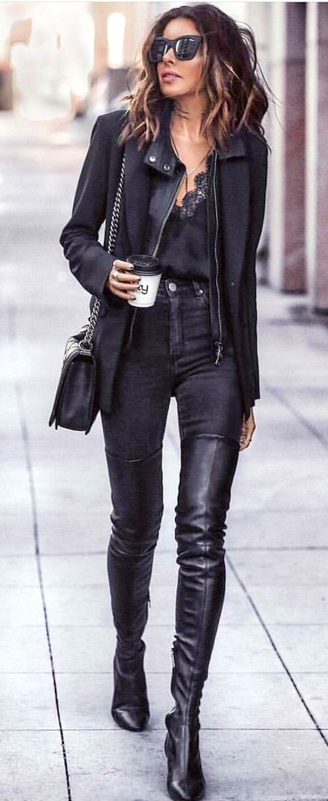 Woman in black full-zip jacket holding disposable cup.