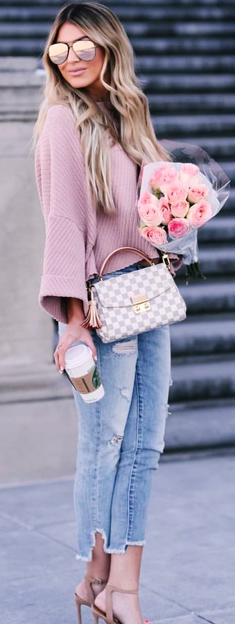 Woman in pink sweater holding bouquet of flowers.