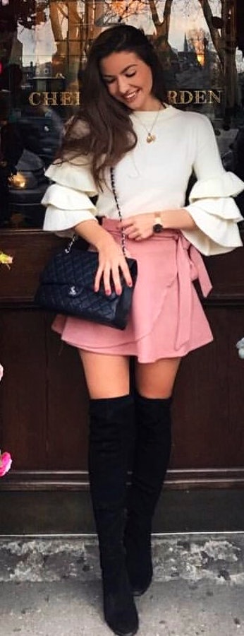 Woman in white scoop-neck long-sleeved dress and pink mini skirt.