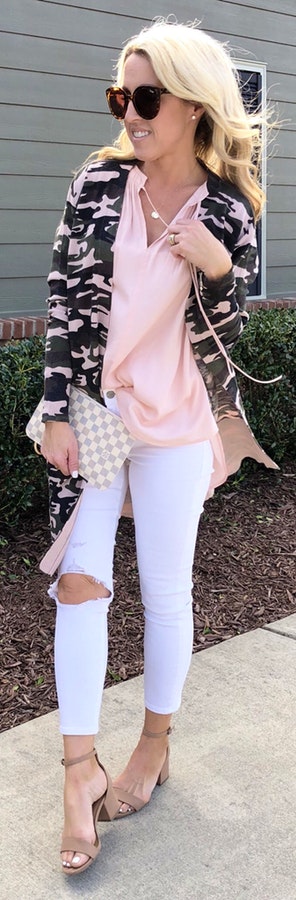 Woman wearing black and pink camouflage jacket and pink shirt with white distress jeans outfit.