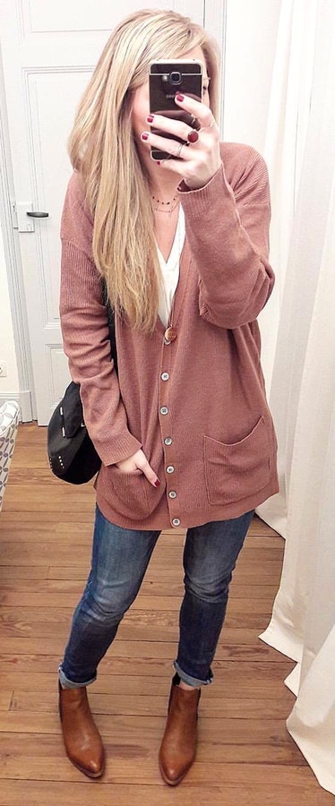 Woman wearing brown button-up jacket holding smartphone.