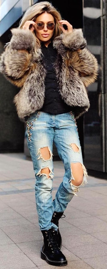 Woman wearing blue ripped jeans, black lace-up boots, and brown fur coat.