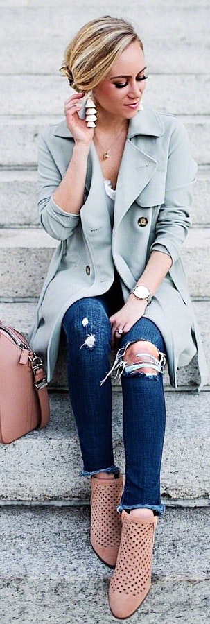 Woman wearing gray leather overcoat and distressed blue fitted jeans.