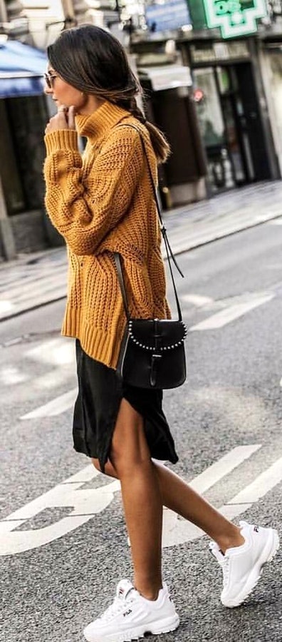 Woman wearing knitted brown sweater and black skirt.