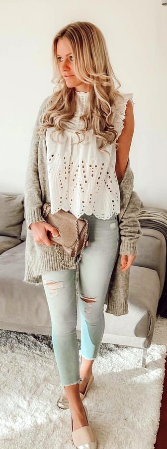 Woman wearing white lace cap-sleeved shirt and distressed blue fitted jeans.