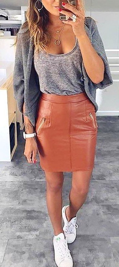 woman wearing grey scoop-neck shirt and brown leather skirt.