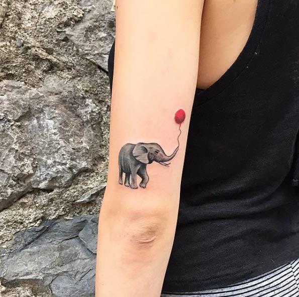 Elephant with a balloon tattoo on back arm.