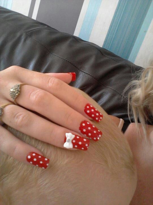 Red polka dot nails with a white bow.