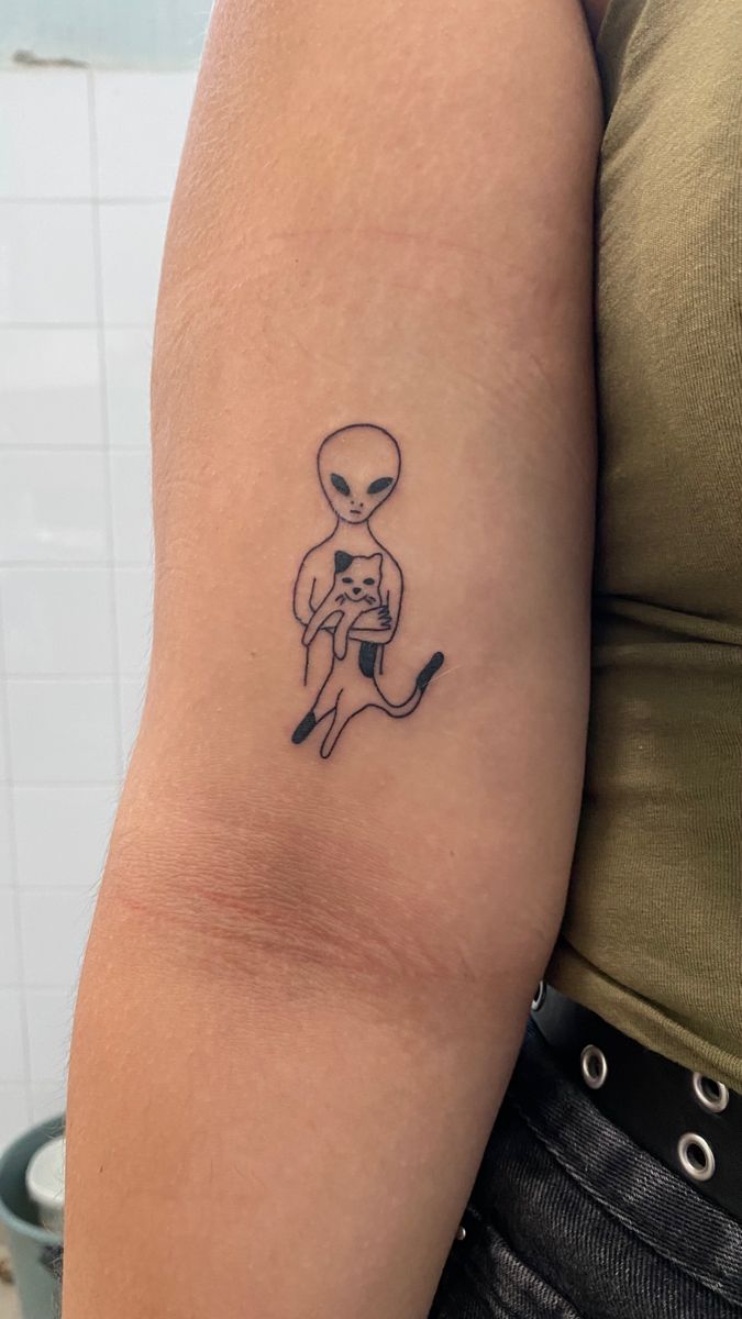 Tattoo of an alien holding a cat
