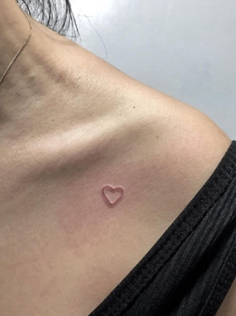 Tiny red ink heart collarbone tattoo